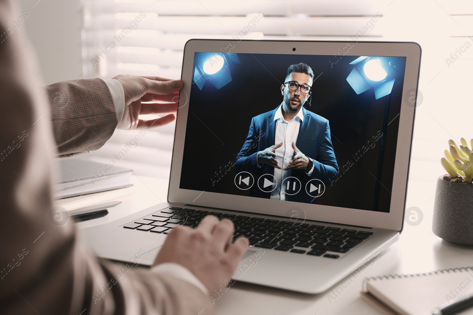 Image of Woman watching performance of motivational speaker on laptop at white table, closeup