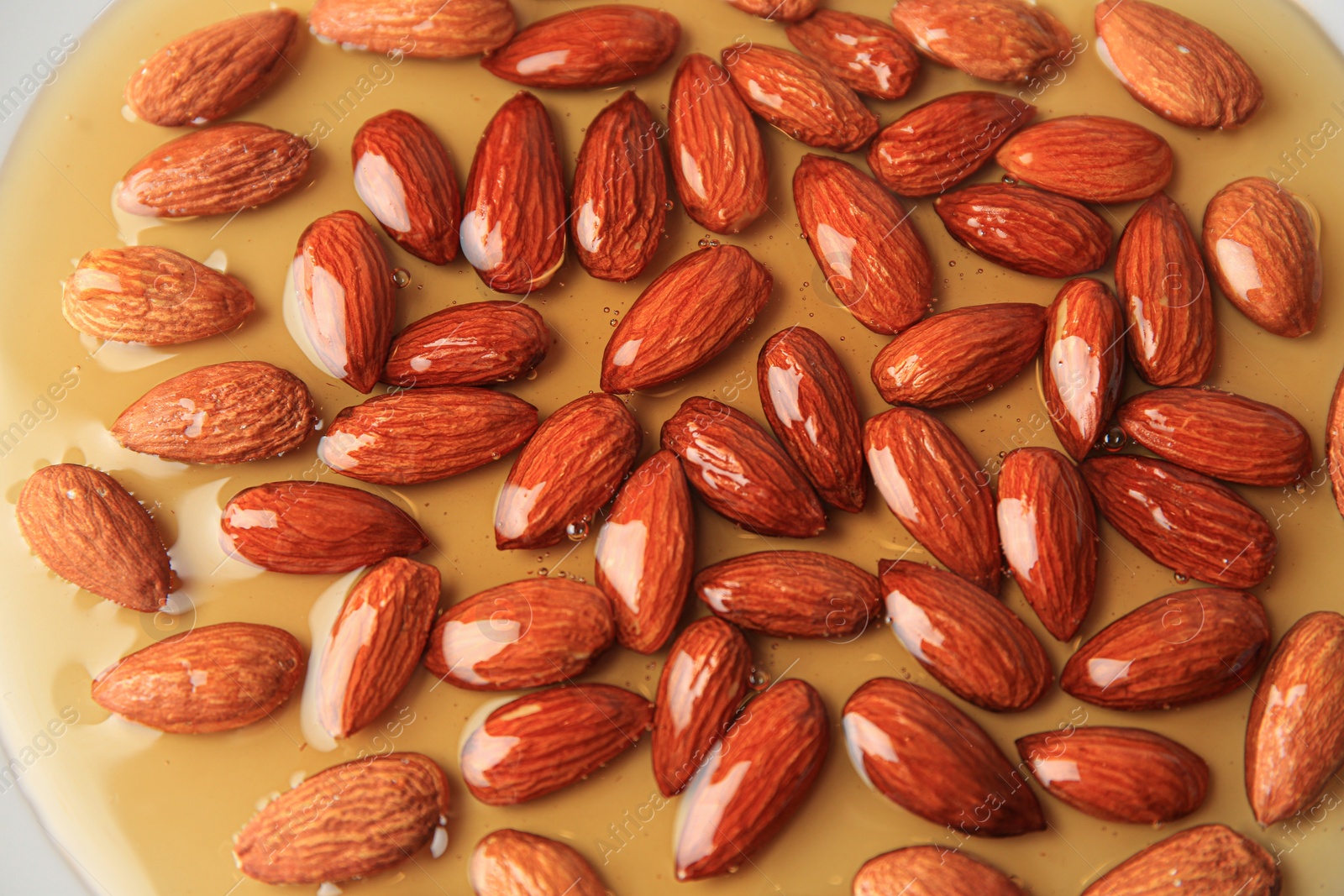 Photo of Tasty almond nuts with honey as background, above view
