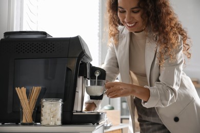 Photo of African American woman preparing fresh aromatic coffee with modern machine in office, closeup