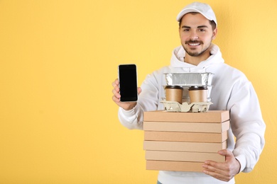 Young man holding orders and smartphone on color background, mockup for design. Online food delivery