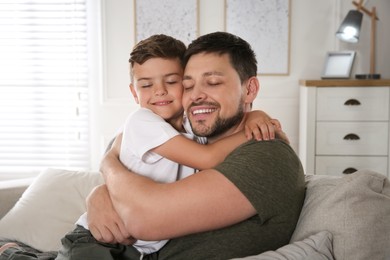 Photo of Father and his son on sofa in living room. Adoption concept