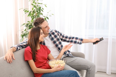 Photo of Happy young couple watching TV on sofa at home