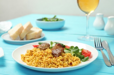 Plate of tasty rice pilaf with meat served on table