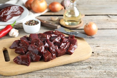 Photo of Cut raw beef liver and products on wooden table, space for text