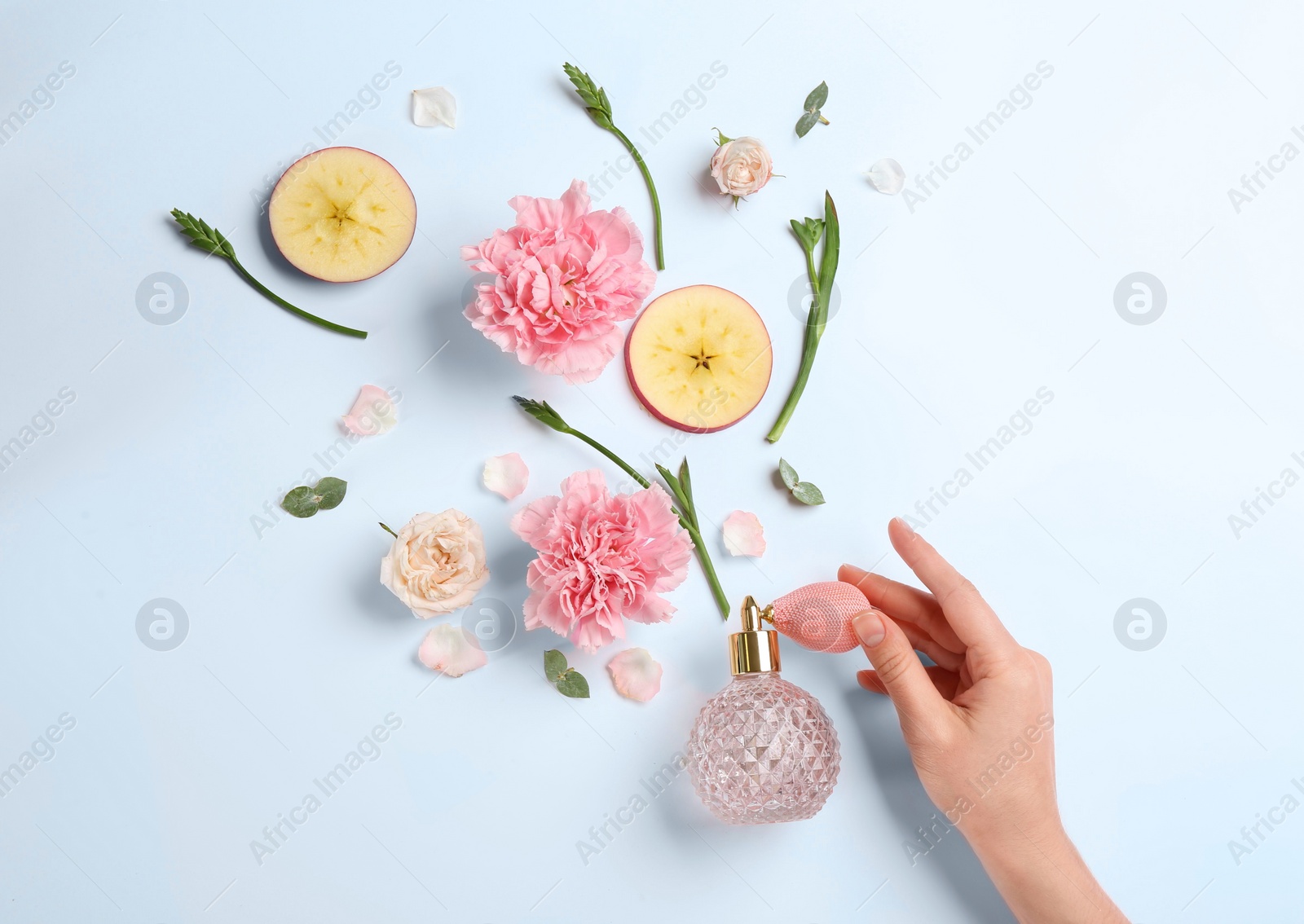 Photo of Top view of woman spraying perfume on white background, apple and flowers representing aroma