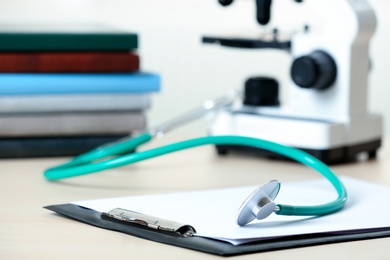 Photo of Clipboard with report and stethoscope on table. Medical students stuff