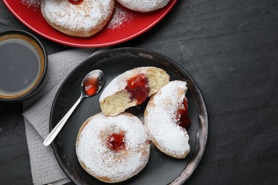 Photo of Delicious jelly donuts served with coffee on black table, flat lay