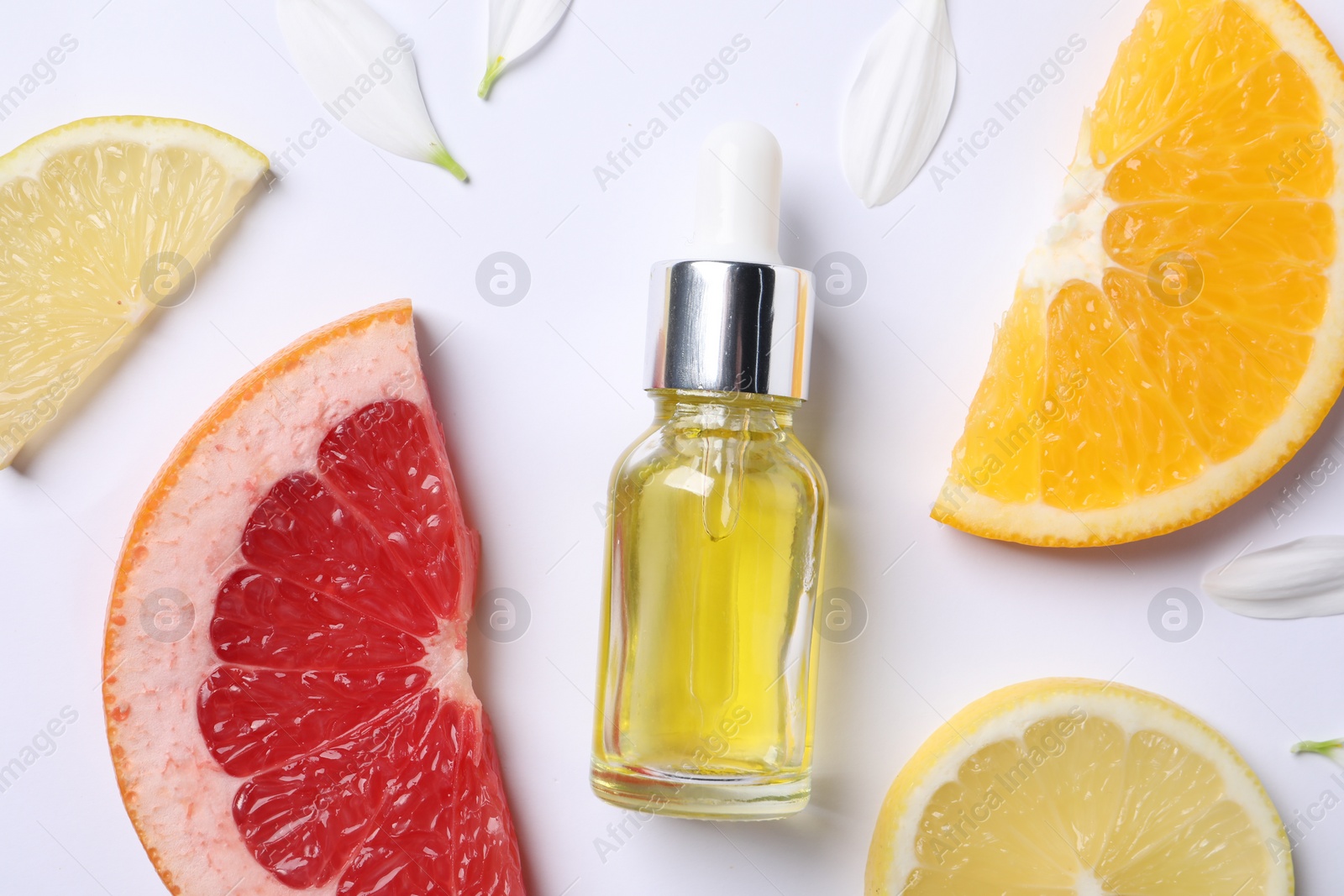 Photo of Bottle of cosmetic serum, flower petals and citrus fruit slices on white background, flat lay