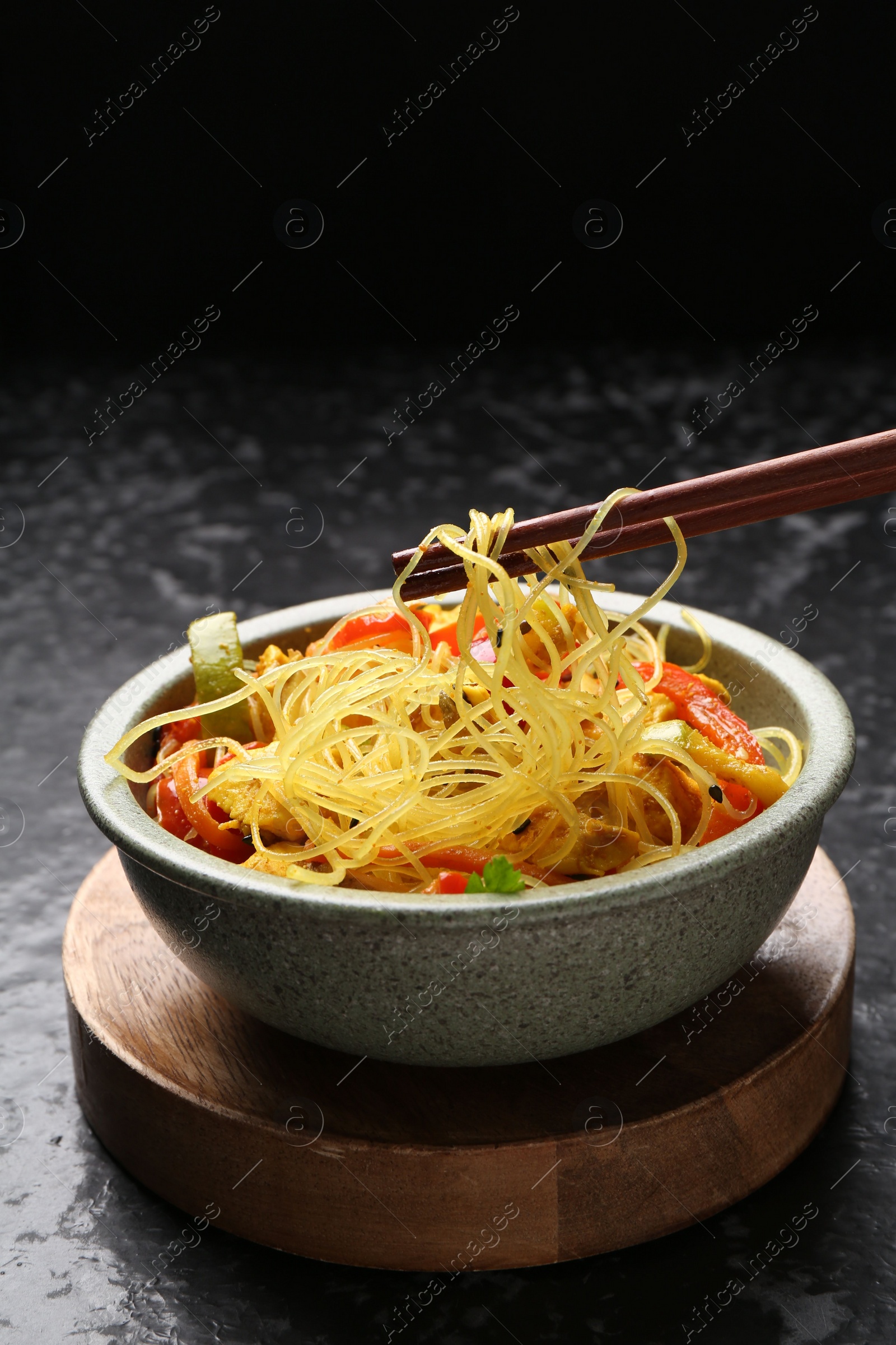 Photo of Stir-fry. Eating tasty noodles with meat and vegetables at dark textured table