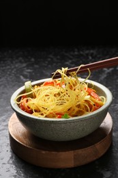 Photo of Stir-fry. Eating tasty noodles with meat and vegetables at dark textured table