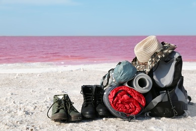 Set of camping equipment with sleeping bag on coast of pink lake