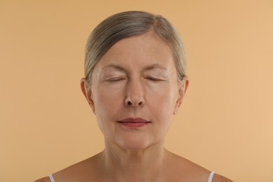 Woman with closed eyes on beige background