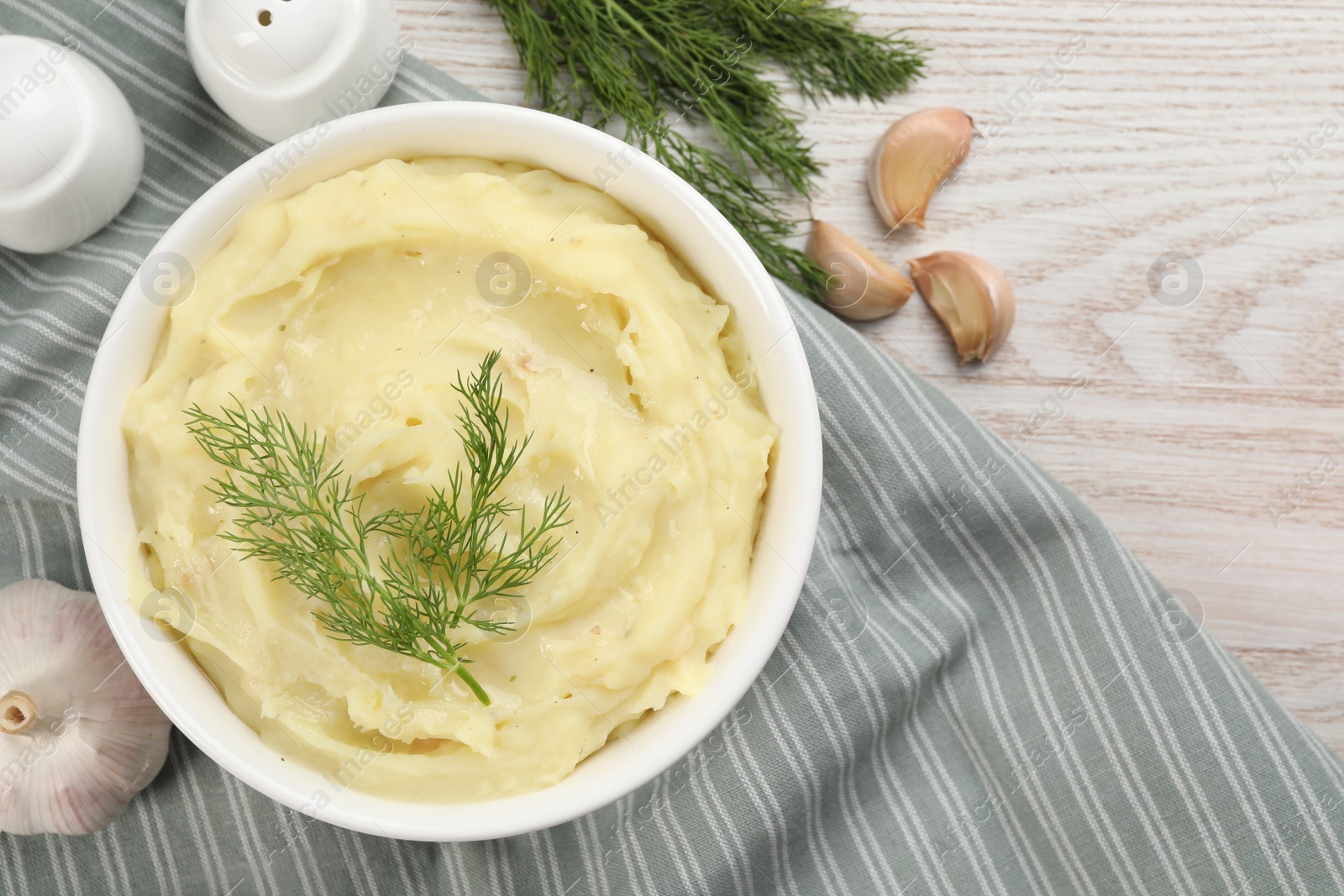 Photo of Bowl of tasty mashed potato with garlic and dill on wooden table, flat lay