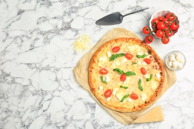 Photo of Delicious pizza with cheese, basil and tomatoes on marble table, top view