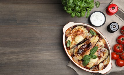 Photo of Delicious eggplant lasagna in baking dish on wooden table, flat lay. Space for text