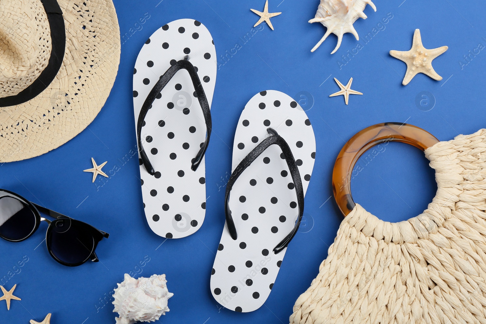 Photo of Flat lay composition with flip flops and beach accessories on blue background