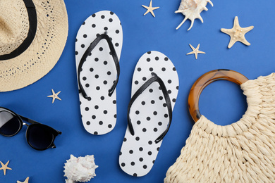 Flat lay composition with flip flops and beach accessories on blue background