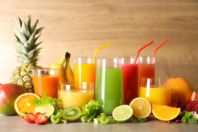 Glasses with different juices and fresh fruits on table