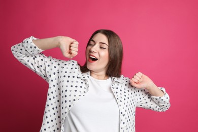 Young tired woman yawning on pink background