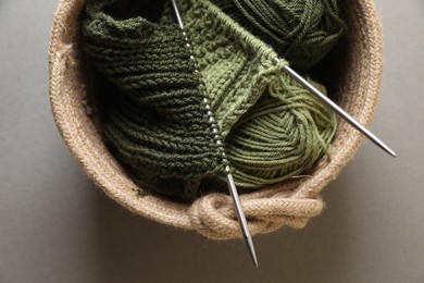 Green knitting, needles and soft yarns on light background, top view