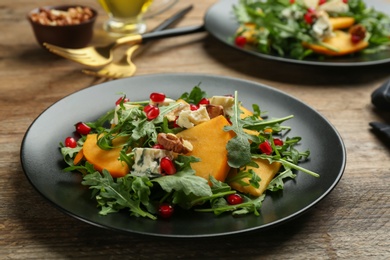 Photo of Delicious persimmon salad with pomegranate and arugula served on wooden table