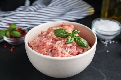 Photo of Raw chicken minced meat with basil on black table, closeup