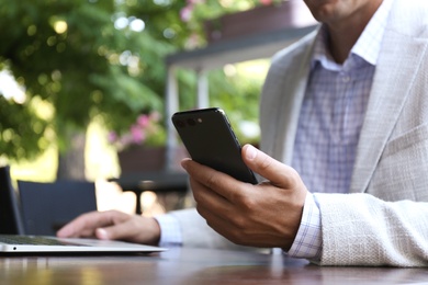 Photo of Businessman with smartphone in outdoor cafe, closeup