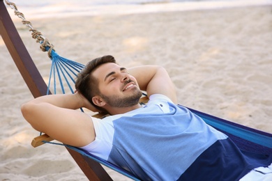 Young man lying in hammock at seaside. Summer vacation