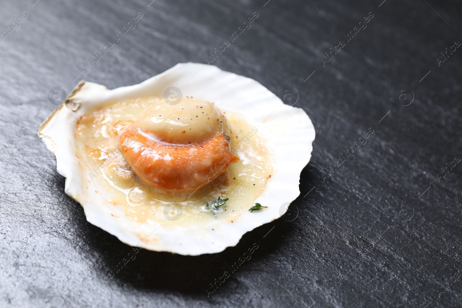 Photo of Fried scallop in shell on black table, closeup. Space for text