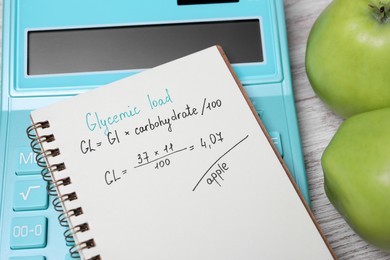 Notebook with calculated glycemic load for apples, calculator and fresh fruits on table, closeup