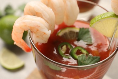 Tasty shrimp cocktail with sauce in glass and lime on light table, closeup