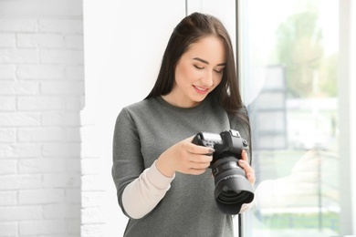 Photo of Young female photographer with professional camera indoors