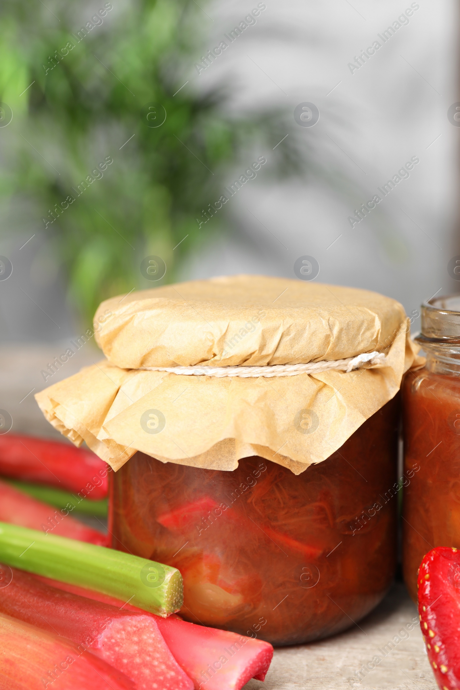 Photo of Tasty rhubarb jam and stems on table. Space for text
