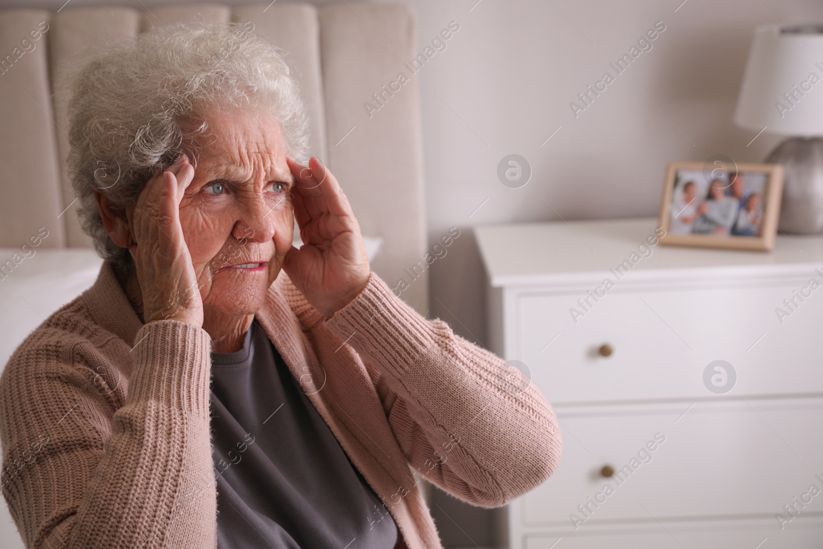 Photo of Senior woman with headache in bedroom at home. Space for text