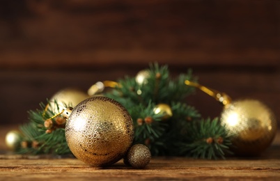 Photo of Beautiful Christmas balls and fir branch on wooden table. Space for text