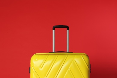 Stylish yellow suitcase with handle on color background