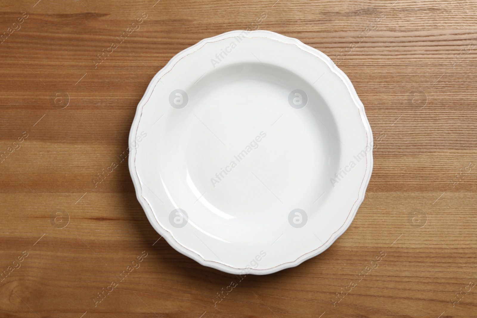 Photo of Empty ceramic plate on wooden table, top view