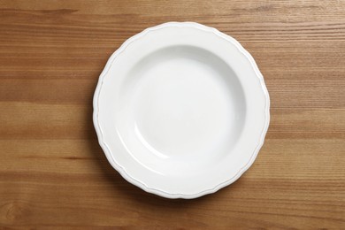 Photo of Empty ceramic plate on wooden table, top view