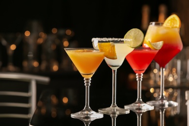 Photo of Different delicious cocktails on black table in bar. Space for text