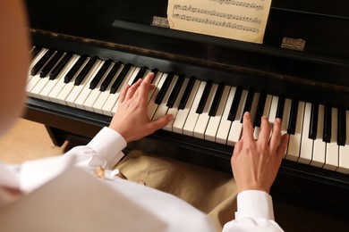 Photo of Young woman playing piano, closeup. Music lesson
