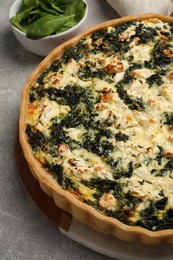 Delicious homemade spinach quiche on light gray table, closeup