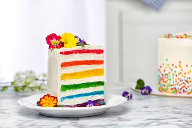 Photo of Slice of delicious rainbow cake with flowers on table