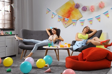 Photo of Young women sleeping in messy room after party