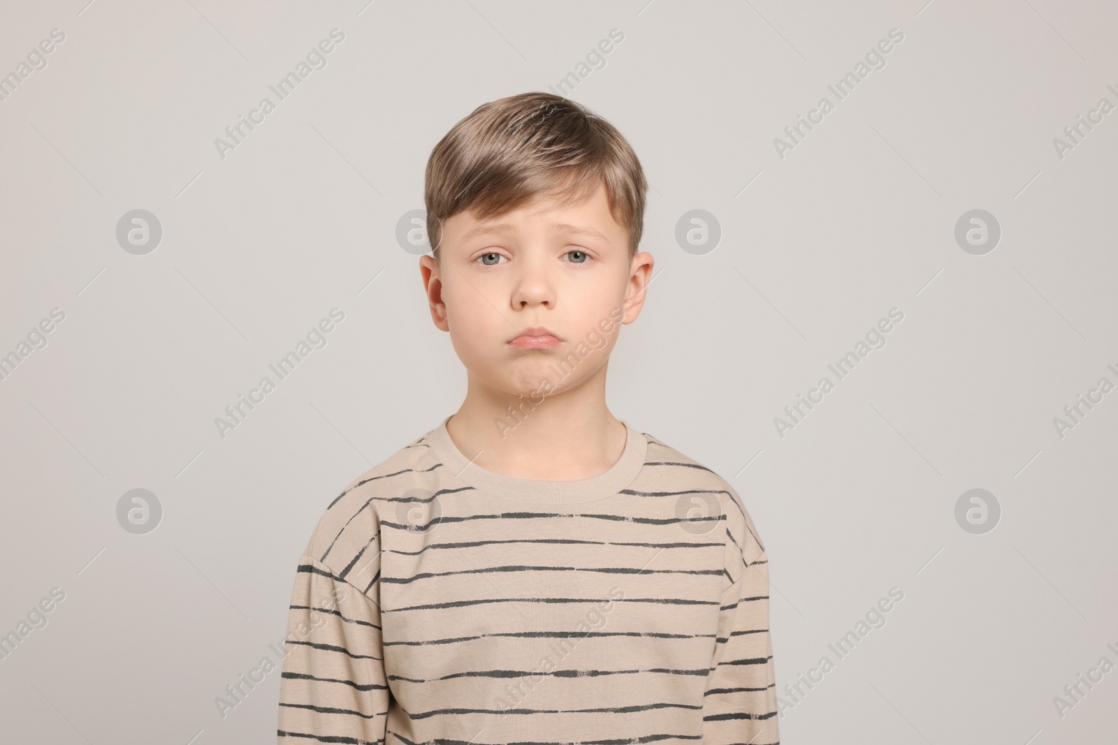 Photo of Upset boy on light grey background. Children's bullying