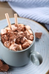 Photo of Cup of aromatic hot chocolate with marshmallows and cocoa powder served on table, closeup