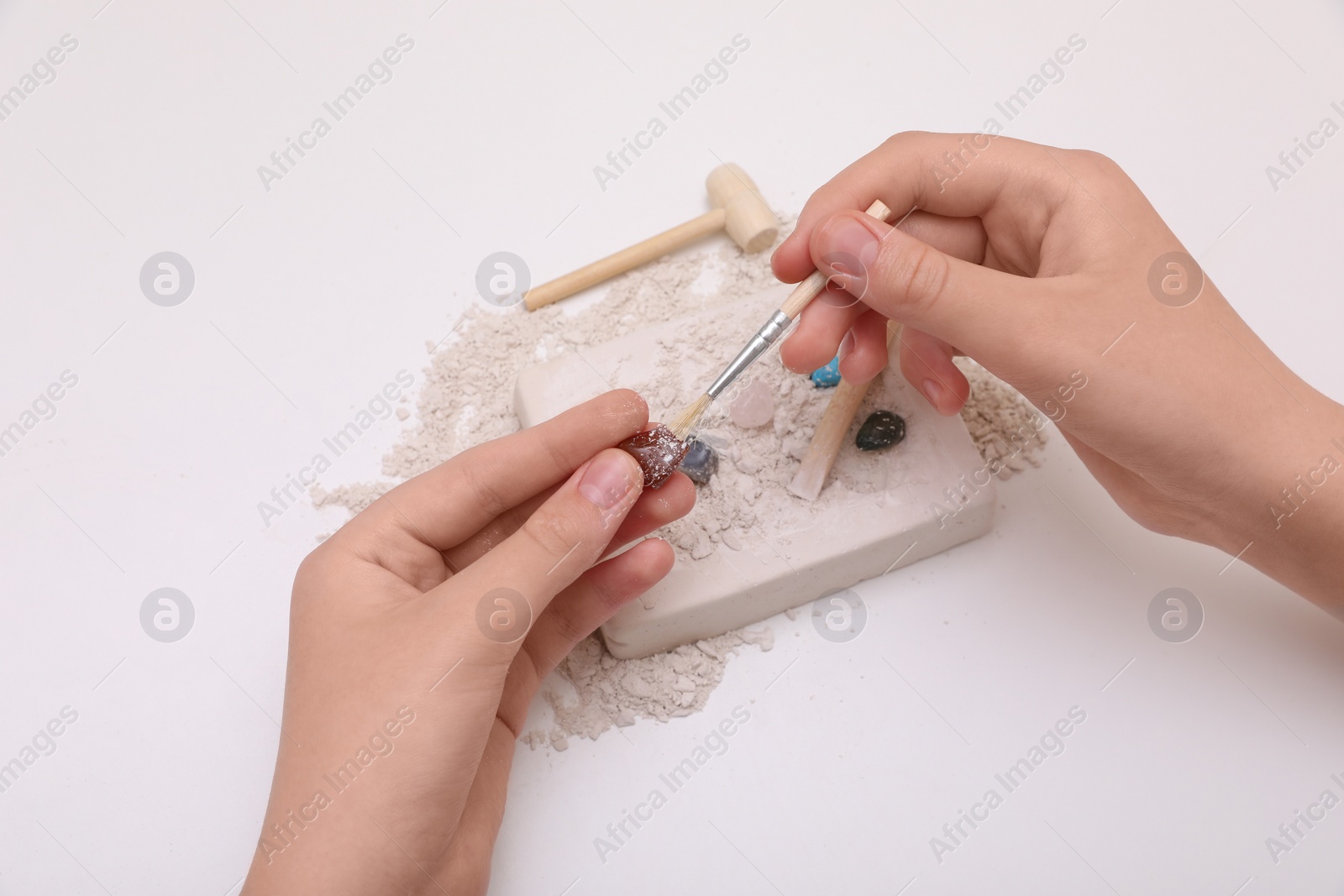 Photo of Child playing with Excavation kit on white background, above view. Educational toy for motor skills