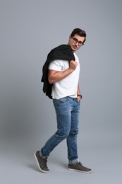 Photo of Handsome young man in casual clothes with black jacket and glasses on grey background