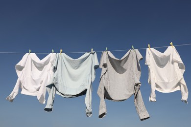 Washing line with drying clothes and clothespins under blue sky