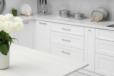 Bouquet of flowers on stylish white wooden table in kitchen, space for text. Interior design