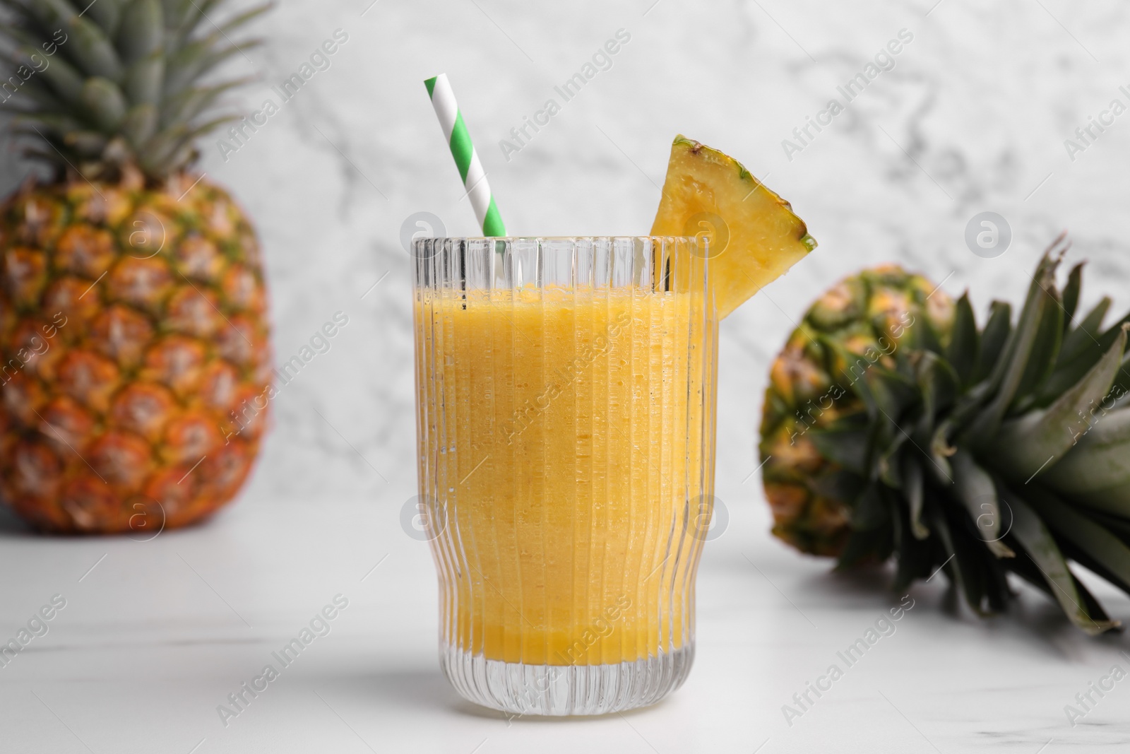 Photo of Tasty pineapple smoothie, whole and cut fruits on white table